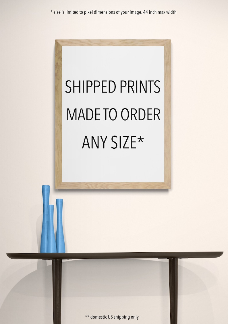 May include: A framed print with the text "SHIPPED PRINTS MADE TO ORDER ANY SIZE*" on a white background. The frame is made of light wood. Three blue vases are on a dark brown table.