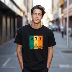 May include: Black t-shirt with a retro-style graphic featuring the numbers 517, a cityscape, and a distressed background.