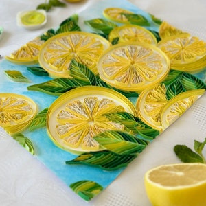 Puede incluir: Una obra de arte de quilling de papel hecha a mano con rodajas de lim&oacute;n y hojas verdes sobre un fondo azul claro. Los limones son amarillos con centros blancos, y las hojas son de varios tonos de verde. Tambi&eacute;n hay medio lim&oacute;n y hojas de menta.