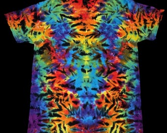 Puede incluir: Una vibrante camiseta teñida con un diseño tie-dye que presenta un caleidoscopio de colores, incluyendo rojo, naranja, amarillo, verde, azul y morado. La camiseta tiene cuello redondo y mangas cortas.