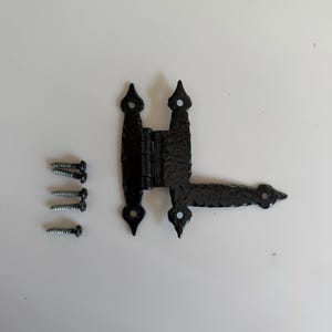 Peut inclure: Charnière en fer forgé noir avec des fleurons décoratifs et une surface texturée. Comprend quatre vis. La charnière est conçue pour une porte ou une armoire. La charnière mesure environ 15 cm de long.