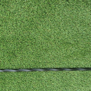 May include: Black metal fire poker with a twisted handle and a hook on the end. The poker is on a green artificial grass surface. The text "TIMEOUT ACCESSORIES" is on a black circle with white leaves around the edge.