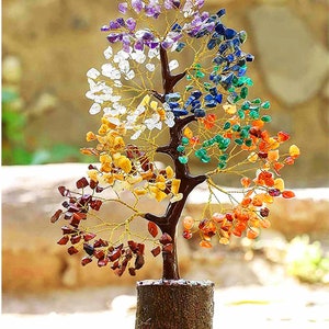 Puede incluir: Un árbol de cristal con siete cristales de diferentes colores que representan los siete chakras. El árbol está hecho de alambre y tiene una base de madera.