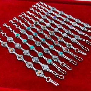 Puede incluir: Un conjunto de 14 pulseras de plata con piedras preciosas de diferentes colores. Cada pulsera tiene un cierre de broche.