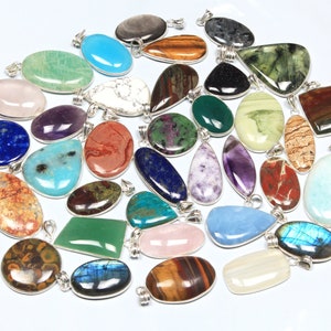 Può includere: Assortimento di ciondoli in pietra preziosa con montature in argento. I ciondoli sono di varie forme e colori, tra cui verde, blu, viola, rosso e marrone.