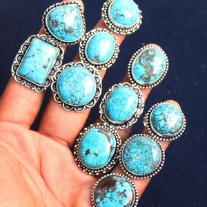 May include: Nine silver rings with turquoise stones of varying shapes and sizes. The rings are all set in silver and have a beaded edge.