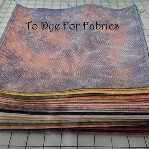 May include: A stack of colorful fabric squares, each with a unique dyed pattern. The top square has the text "To Dye For Fabrics" in a script font. The fabrics display a range of colors, including pink, purple, yellow, and green.