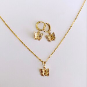 May include: A gold necklace and earrings set featuring a delicate butterfly pendant and matching butterfly hoop earrings.