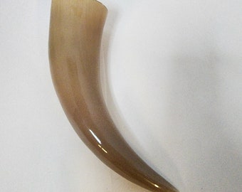 May include: A brown drinking horn made from natural materials. The horn is curved and has a smooth, polished finish.