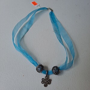 May include: A blue ribbon necklace with a silver Celtic knot pendant and two silver beads.