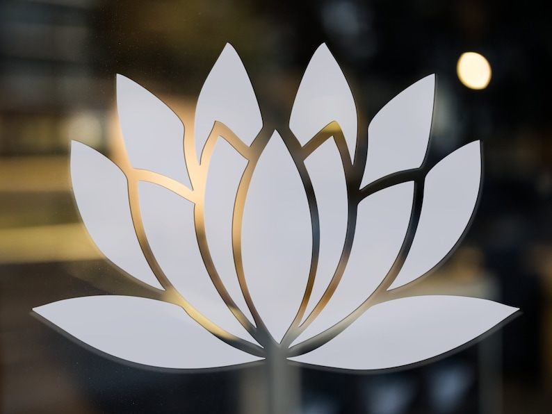 May include: A white lotus flower design on a frosted glass surface. The design is simple and elegant, with a delicate outline.