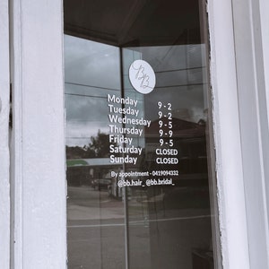 K&ouml;nnte beinhalten: Eine wei&szlig;e Beschilderung mit schwarzem Text auf einer Glast&uuml;r, die die Gesch&auml;ftszeiten eines Salons namens "BB" auflistet. Das Schild zeigt "Montag 9-2, Dienstag 9-2, Mittwoch 9-5, Donnerstag 9-9, Freitag 9-5, Samstag GESCHLOSSEN, Sonntag GESCHLOSSEN". Das Schild enth&auml;lt auch Kontaktinformationen: "Nach Vereinbarung - 0419094332 @bb.hair_ @bb.bridal_"