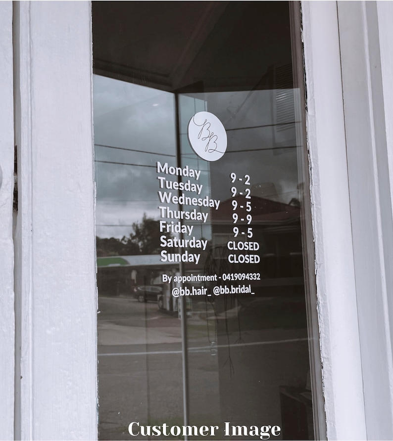 K&ouml;nnte beinhalten: Eine wei&szlig;e Beschilderung mit schwarzem Text auf einer Glast&uuml;r, die die Gesch&auml;ftszeiten eines Salons namens "BB" auflistet. Das Schild zeigt "Montag 9-2, Dienstag 9-2, Mittwoch 9-5, Donnerstag 9-9, Freitag 9-5, Samstag GESCHLOSSEN, Sonntag GESCHLOSSEN". Das Schild enth&auml;lt auch Kontaktinformationen: "Nach Vereinbarung - 0419094332 @bb.hair_ @bb.bridal_"