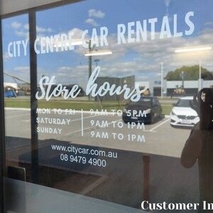 K&ouml;nnte beinhalten: Eine Glast&uuml;r mit einem wei&szlig;en Schild, auf dem "CITY CENTRE CAR RENTALS" und "Store hours" steht. Das Schild listet die Gesch&auml;ftszeiten von Montag bis Freitag, Samstag und Sonntag auf. Die Telefonnummer und die Website sind ebenfalls auf dem Schild angegeben.