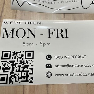 K&ouml;nnte beinhalten: Ein wei&szlig;es Schild mit schwarzem Text, auf dem steht "WE'RE OPEN: MON - FRI 8am - 5pm". Ein schwarz-wei&szlig;es QR-Code befindet sich in der linken unteren Ecke. Das Schild enth&auml;lt auch ein Telefonsymbol mit dem Text "1800 WE RECRUIT", ein E-Mail-Symbol mit dem Text "admin@smithandco.net.au" und ein Globussymbol mit dem Text "www.smithandco.net.au".