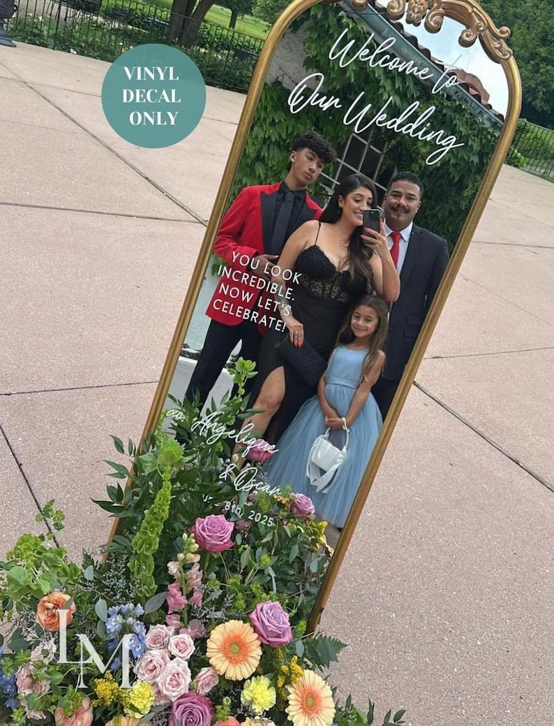 Op de afbeelding: Een boogvormige vloerspiegel met een gouden lijst voorzien van witte vinyl belettering met de tekst Welcome to Our Wedding, YOU LOOK INCREDIBLE. NOW LET'S CELEBRATE!, en Angelique & Oscar 8th, 2025. Een groenblauwe cirkel vermeldt VINYL DECAL ONLY.