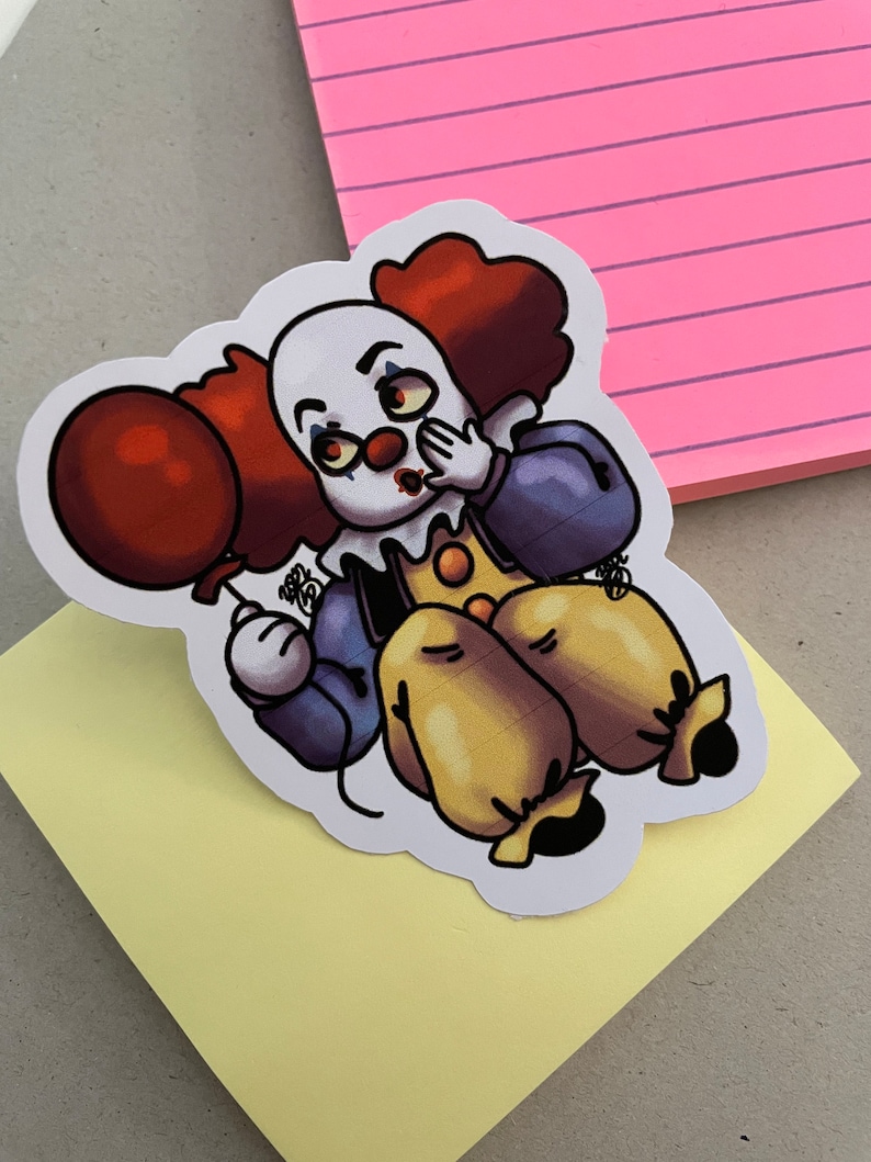 May include: A sticker of a cartoon clown with red hair, a white face, and a red nose. The clown is holding a red balloon and has a surprised expression on its face.