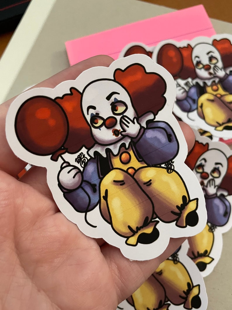 May include: A sticker of a cartoon clown with red hair, a red balloon, and a blue and purple outfit. The clown is holding its hand over its mouth and has a surprised expression on its face.