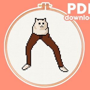 Könnte beinhalten: Kreuzstichmuster einer Katze, die eine braune Hose trägt. Das Muster befindet sich in einem hölzernen Stickrahmen. Der Text "PDF-Download" befindet sich in der oberen rechten Ecke des Bildes.