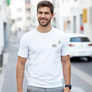 Può includere: T-shirt bianco girocollo con una piccola grafica nera di un cervello e una lampadina collegati da una linea. La t-shirt è indossata da una persona in un ambiente stradale.