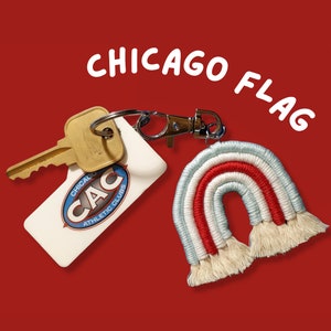 May include: A white keychain with the text "Chicago Athletic Club" and a blue logo. The keychain is attached to a silver key ring with a key and a red, white, and blue crocheted rainbow charm.