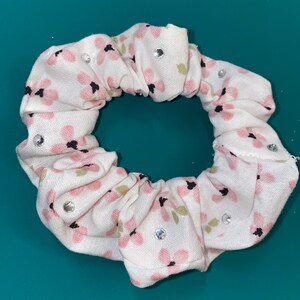 May include: White scrunchie with a pink floral pattern and clear rhinestones.