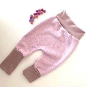 Può includere: Pantaloni per neonati rosa e marroni con un motivo maculato. I pantaloni hanno una cintura larga e gambe con polsini.