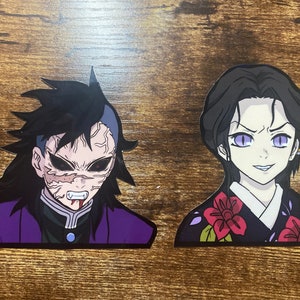 May include: Two anime character stickers, one with a purple and black outfit and the other with a black and red outfit. The character with the purple and black outfit has a menacing expression with sharp teeth and red eyes. The character with the black and red outfit has a more sinister expression with purple eyes.