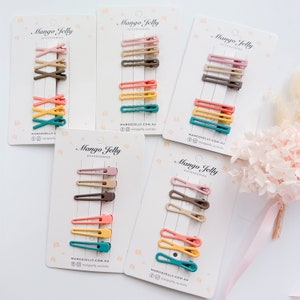 May include: Five sets of colorful hair clips on white cards. Each set includes four clips in different colors and shapes. The cards have the text "Mango Jelly Accessories" and the website address "mangojelly.com.au".