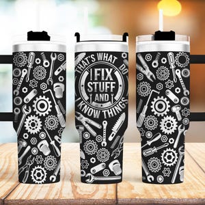 May include: Two stainless steel tumblers with black lids and handles. The tumblers are covered in a black and white design of tools and gears. The tumbler on the right has the text "That's what I fix stuff and I know things do" on the front.