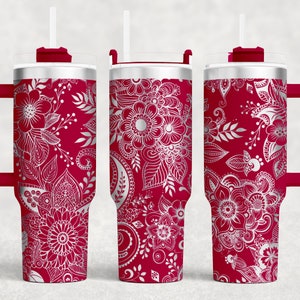 May include: Three stainless steel tumblers with a red base and a white floral design. The tumblers have lids and straws.