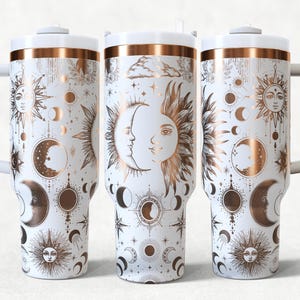 Puede incluir: Vaso de viaje blanco con un diseño celestial que presenta soles, lunas, estrellas y constelaciones en color cobre. El vaso tiene una tapa blanca y una banda de color cobre alrededor de la parte superior.