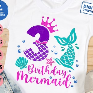 Puede incluir: Una camiseta blanca con un número 3 morado con un diseño de cola de sirena, una corona y el texto "Birthday Mermaid".
