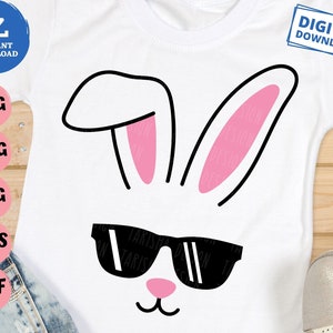 May include: A white t-shirt with a black outline of bunny ears with pink inside. The bunny has black sunglasses and a pink nose and mouth.
