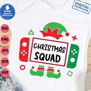 May include: A white t-shirt with a red and green Christmas Squad design featuring a video game controller, an elf hat, and elf shoes. The text "Christmas Squad" is written in black.