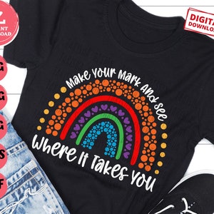 May include: A black t-shirt with a rainbow design made of colorful circles and the text "Make your mark and see where it takes you".