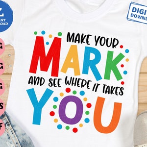 May include: A white t-shirt with the text "Make your mark and see where it takes you" in rainbow colors. The text is surrounded by colorful dots.