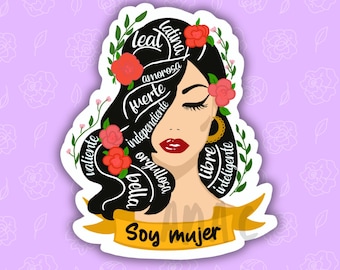 May include: A die-cut sticker featuring a stylised illustration of a person with long black hair adorned with red flowers and green leaves. The hair contains white text including leal, latina, amorosa, fuerte, independiente, valiente, bella, orgullosa, libre, inteligente. A yellow banner at the bottom reads Soy mujer.