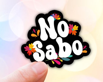 May include: A black and white sticker with the text "No Sabo" in white, surrounded by colorful flowers. The sticker is being held by a hand.