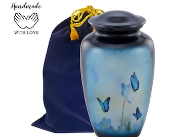 Puede incluir: Urna de cremación azul y blanca con un diseño de mariposa. La urna está hecha de metal y tiene un acabado pulido. Viene con una bolsa de terciopelo azul.