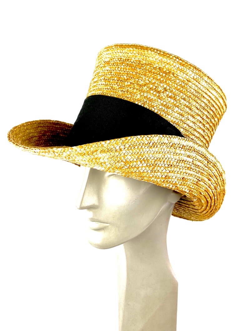 May include: A straw hat with a black band around the crown. The hat is tall and has a wide brim.