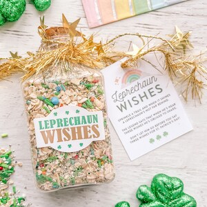 May include: A clear glass jar filled with a mixture of oats, green sprinkles, and other colorful candies. The jar has a gold lid and is decorated with a gold ribbon and a green shamrock. A tag attached to the jar reads "Leprechaun Wishes" and includes a rhyme about leprechauns and wishes.