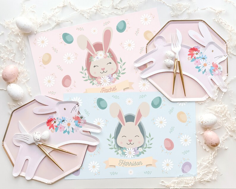 May include: Two pastel-colored placemats with bunny illustrations and floral accents. The placemats feature the names "Rachel" and "Harrison".