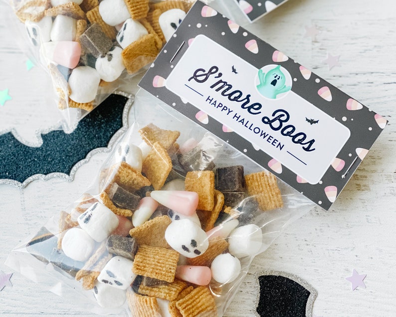 May include: A clear plastic bag filled with a Halloween snack mix. The bag has a black and white label that says "S'more Boos - Happy Halloween" with a ghost illustration. The snack mix includes mini marshmallows, chocolate squares, graham cracker squares, and pink and white candy corn.