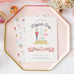 May include: A pink and white invitation with a snow globe illustration featuring a nutcracker and a ballerina. The text reads "Please join us for a Magical Day Rachel is turning One November 22 at 12:30pm 123 Center Street, London ON Please RSVP to metomspon@hotmail.com"
