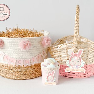 May include: Two Easter baskets with pink and white bunny decorations. One basket is made of woven wicker and the other is a white rope basket with pink pom-poms. Both baskets have a pink banner with the name "Rachel" on them.