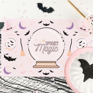 Op de afbeelding: Roze en witte Halloween-placemat met een kristallen bol-ontwerp en de tekst "Spooky Magic".