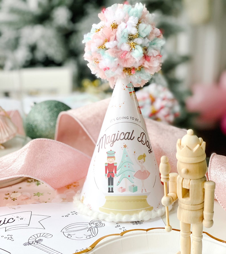 May include: A party hat with a pom-pom top and the text "It's Going to Be a Magical Day." The hat features illustrations of a nutcracker, Christmas tree, and ballerina. A wooden nutcracker figurine is also present.