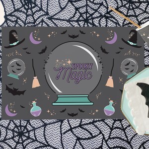 Op de afbeelding: Een zwart-wit Halloween-placemat met een griezelige magische kristallen bol, vleermuizen, sterren, manen, heksenhoeden en bezems. De tekst "Spooky Magic" staat in paars op de kristallen bol.