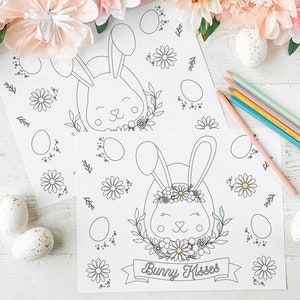 May include: Two printable coloring pages featuring a bunny rabbit with a flower crown and the text "Bunny Kisses". The pages are surrounded by decorative elements like flowers and eggs.